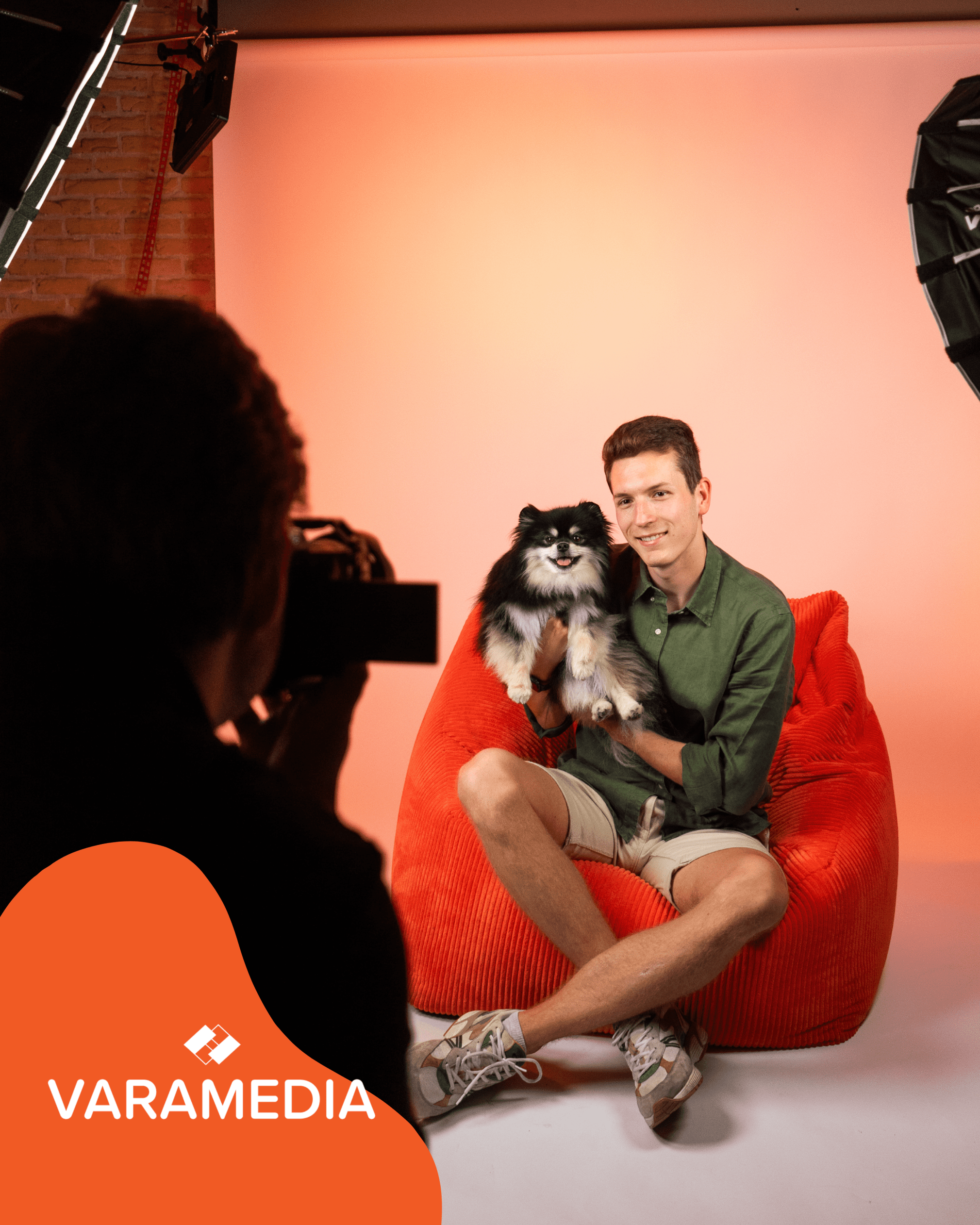 Fotoshoot met man op rode zitzak die een Spits hond vasthoudt