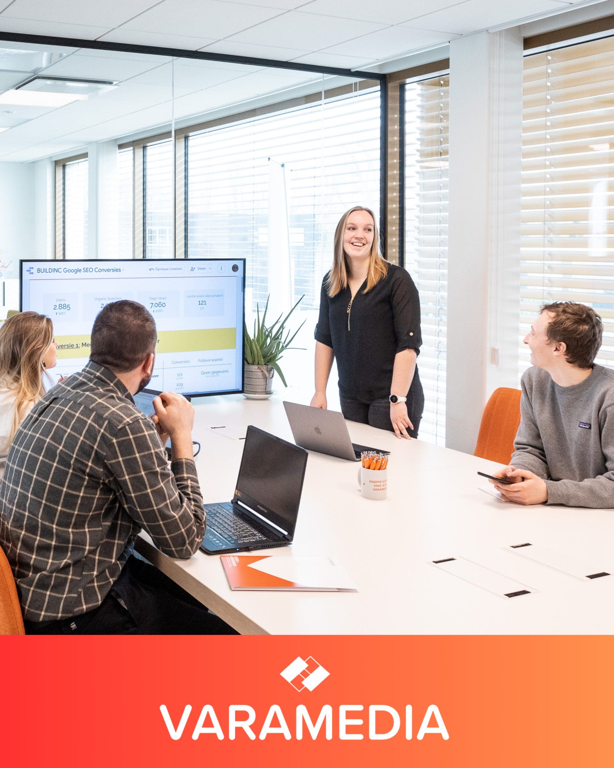 Vrouw presenteert social media strategie aan collega's in vergaderruimte