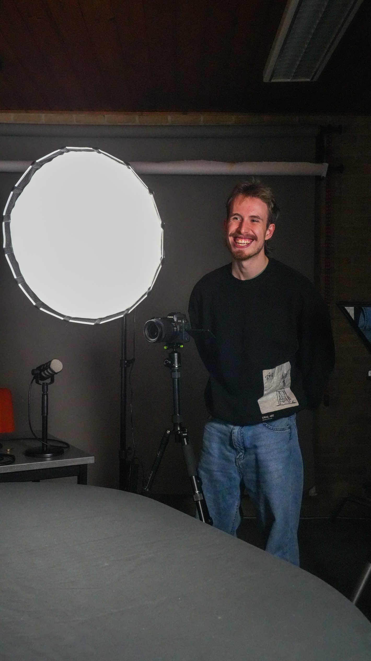 Lachende man in studio naast grote ronde softbox lamp
