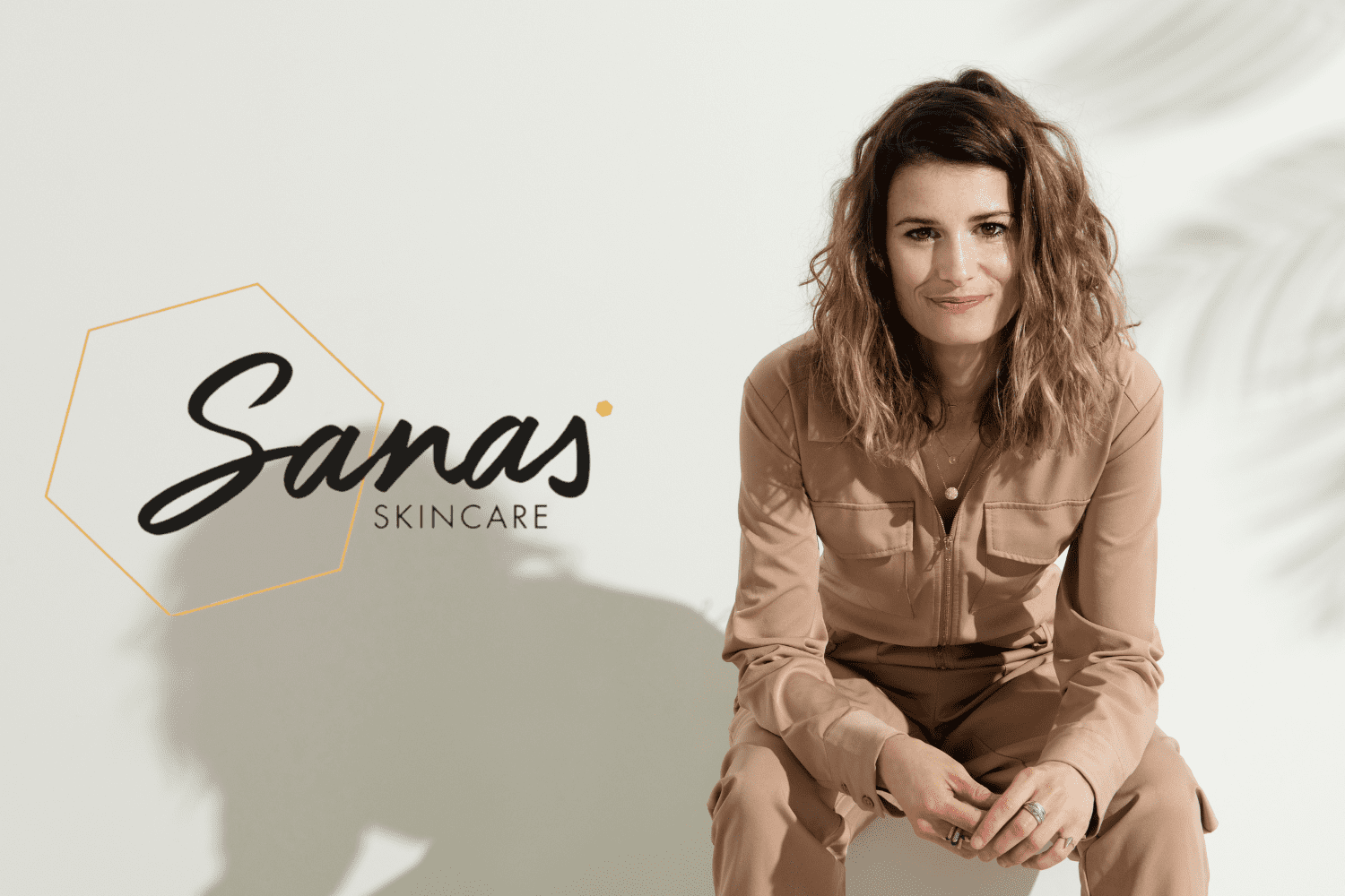 Vrouw in beige outfit naast het logo van Sanas Skincare