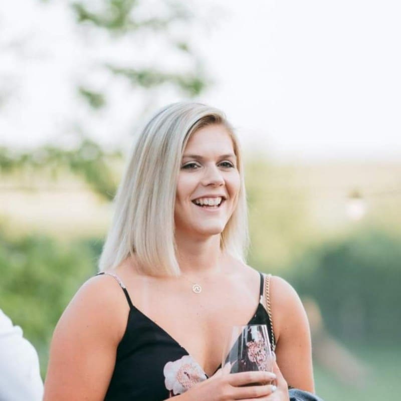 Lachende blonde vrouw met glas op buitenlocatie in zomerse sfeer
