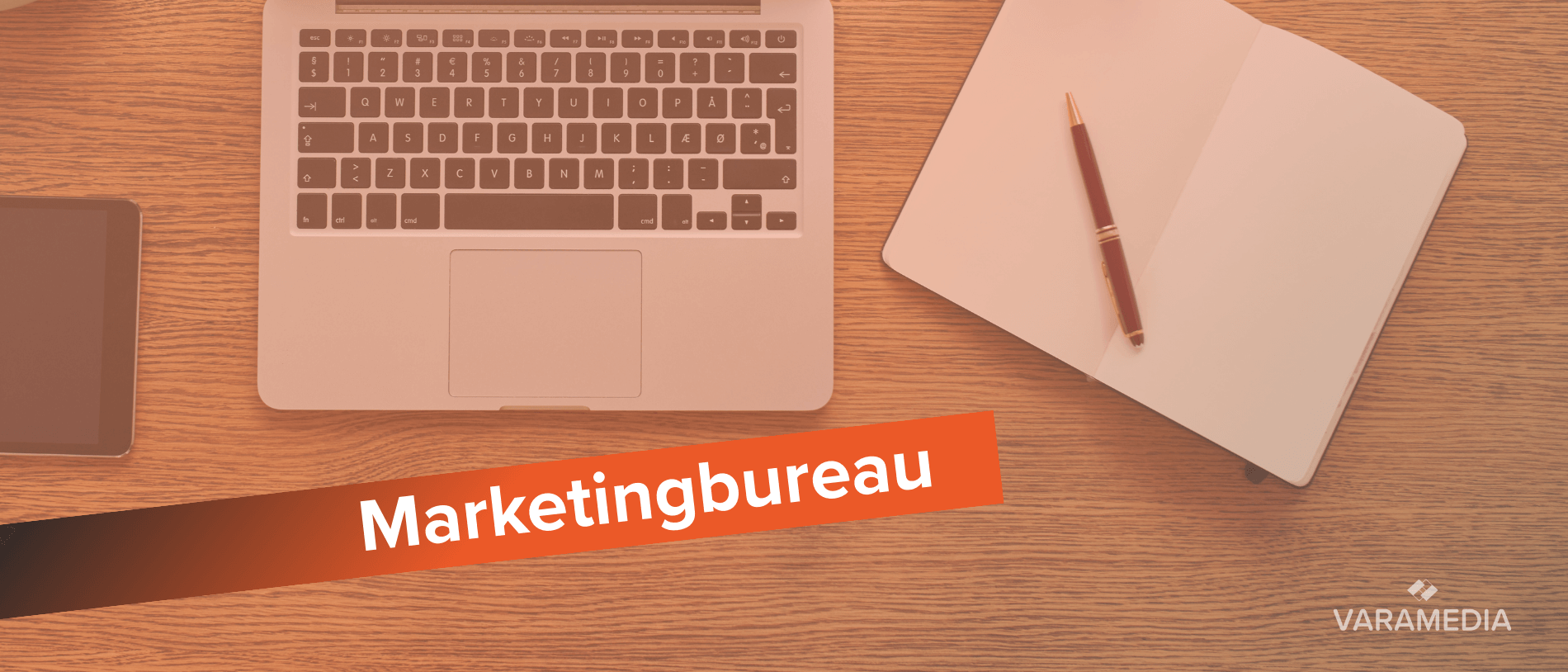 Laptop en notitieboek op houten bureau met tekst marketingbureau