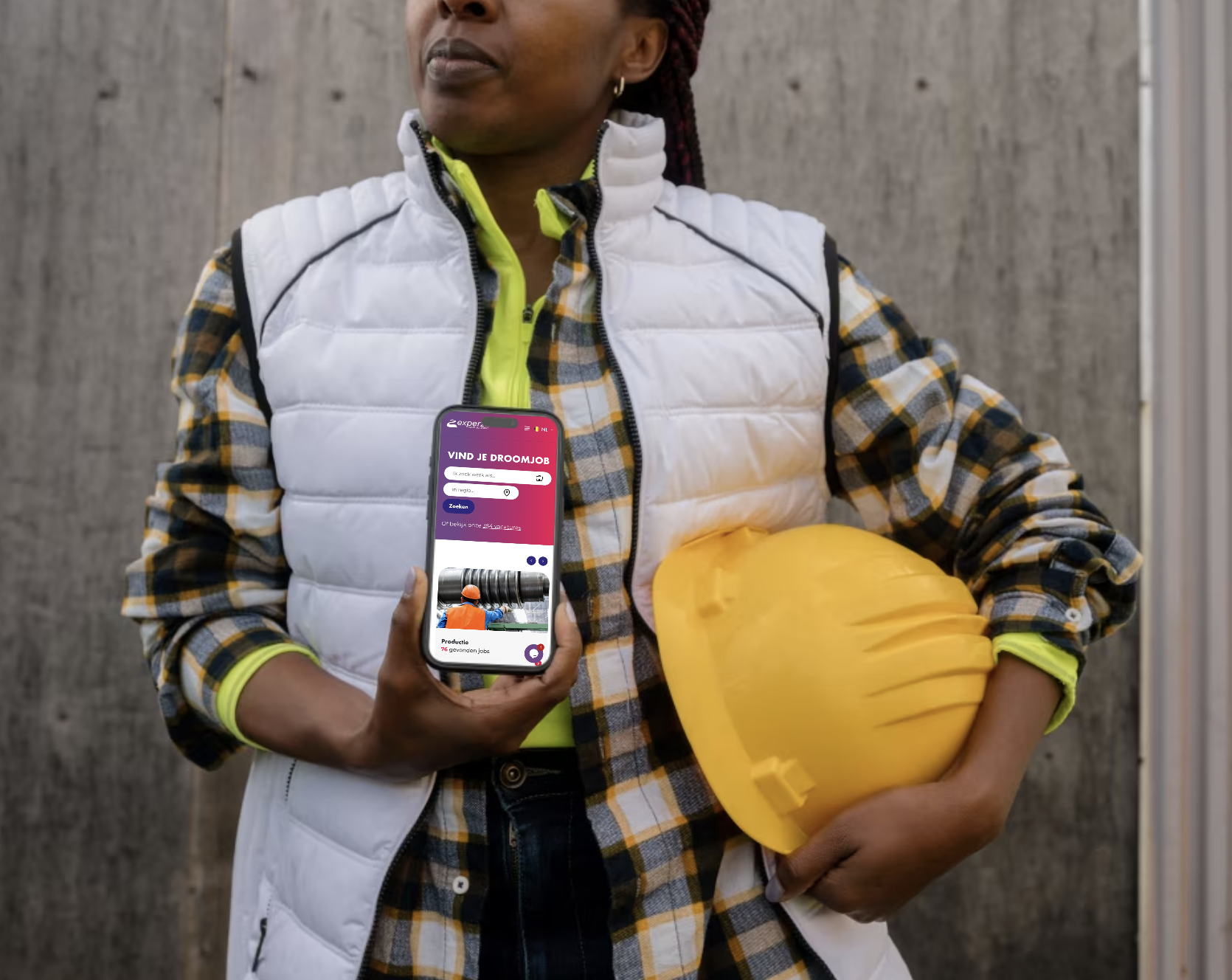 Vrouw met gele bouwhelm en smartphone toont Experza-app